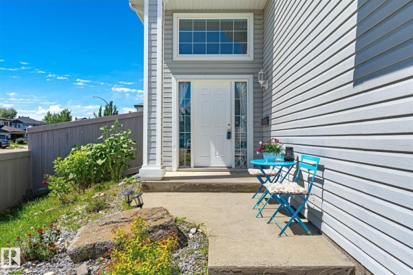 Close-up of the front door with a small blue table and chairs on the concrete porch. - 14908 137 St Nw, Edmonton