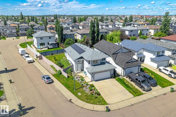 Aerial view of a residential neighbourhood with multiple houses and green lawns under a blue sky. - 14908 137 St Nw, Edmonton