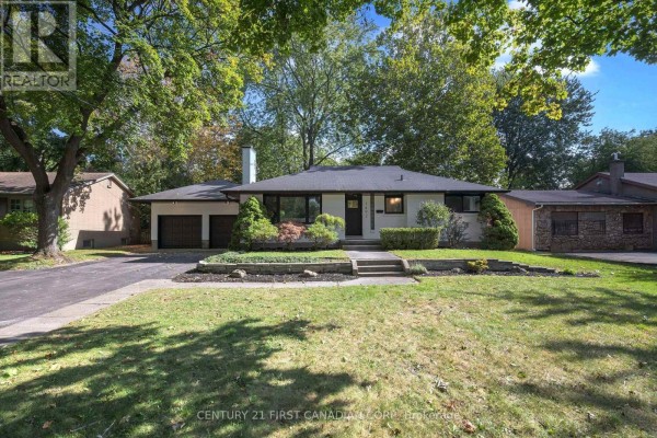Front exterior with a large tree in the foreground and a grey stone foundation. - 1492 North Vernon Avenue, London North