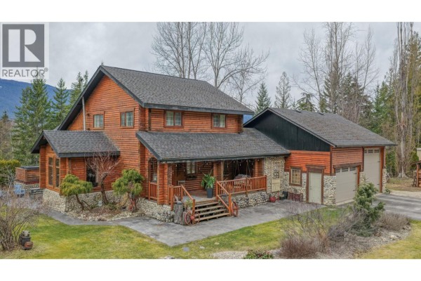 Entrance hall with log walls, white door, wooden bench, and stone accent wall. - 1495 6 Highway, Nakusp