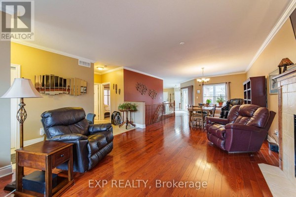 Spacious living area featuring hardwood floors, recliners, and a fireplace. - 1496 Queensdale Avenue, Ottawa