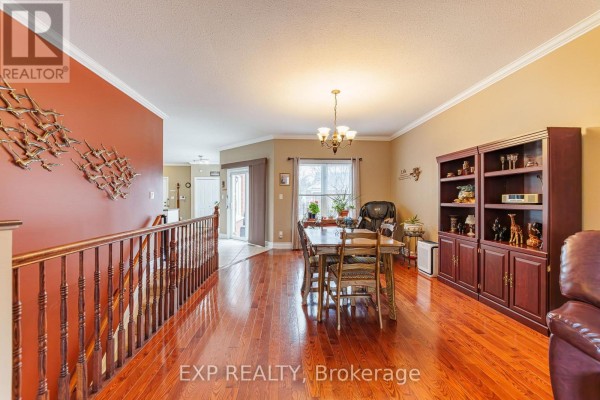 Dining area with a wooden table and chairs, hardwood floors, and a large bookshelf. - 1496 Queensdale Avenue, Ottawa