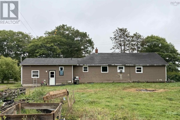 Rear exterior view of the brown wood-sided house with a door, windows, and yard. - 14967 Highway 1, Wilmot