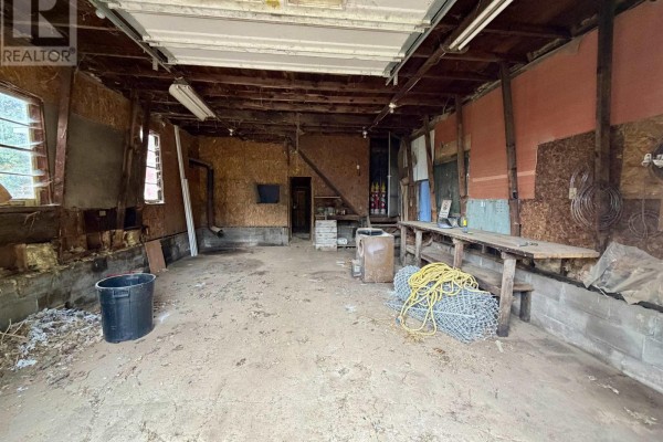 Interior view of a cluttered, unfinished garage with workbenches and exposed wood beams. - 14967 Highway 1, Wilmot