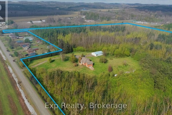 Aerial view showing the property boundaries with wooded areas and nearby homes in the distance. - 1497 Pentecostal Road, Hamilton Township