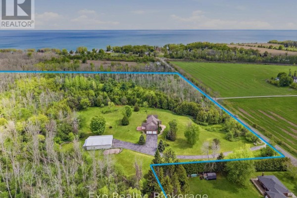 Aerial view of the property with a lake in the background and fields surrounding the area. - 1497 Pentecostal Road, Hamilton Township