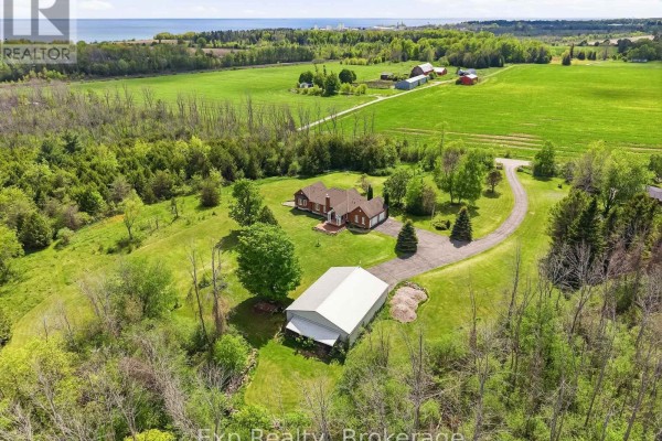 Aerial view of the house featuring a landscaped front yard and surrounding trees. - 1497 Pentecostal Road, Hamilton Township