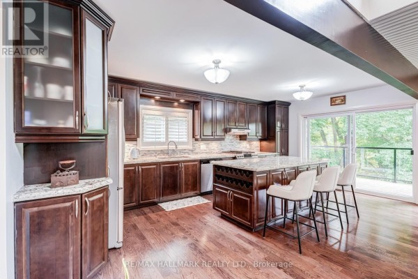Dark wood kitchen with granite countertops, an island with seating, and stainless steel appliances. - 1499 Ashington Court, Mississauga