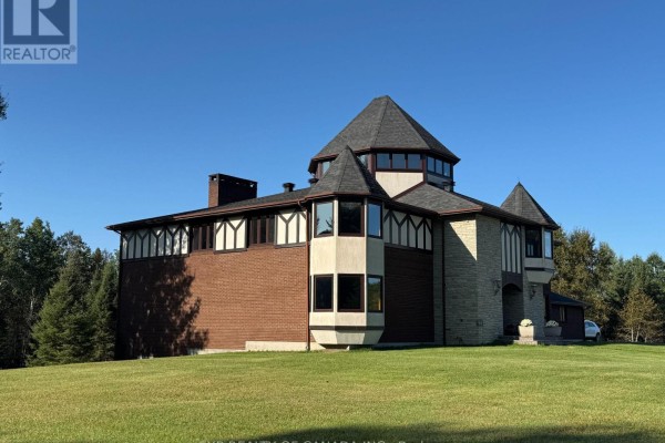 Aerial view of the property showcasing the large house, circular driveway, and surrounding forested landscape. - 1499 Kraft Creek Road, Timmins