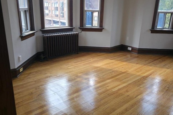 Empty corner room with hardwood floors, dark wood trim, and large radiator. - 15 - 35 Jane Street, Toronto