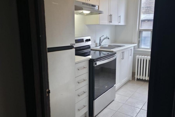 Small white kitchen with stainless steel appliances and tiled floor. - 15 - 35 Jane Street, Toronto