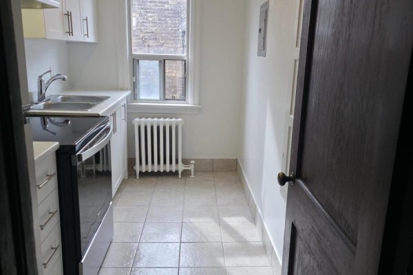 View of white kitchen cabinets, sink, oven, and tiled floor from doorway. - 15 - 35 Jane Street, Toronto