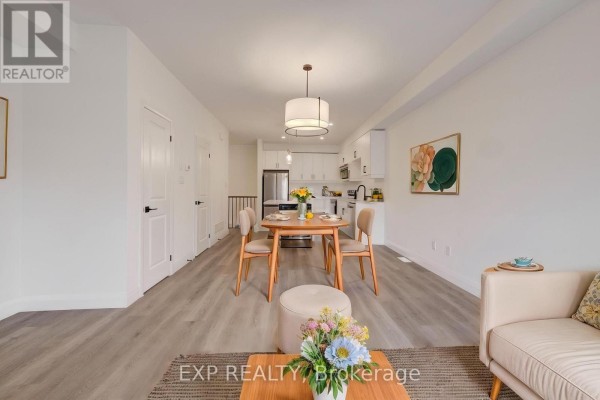 Dining area with wooden table and chairs adjacent to a white kitchen. - 15 - 3900 Savoy Street, London South