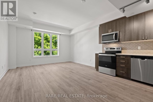 Bright living room with a large window overlooking green trees and a wooden staircase. - 15 - 4045 Hickory Drive, Mississauga