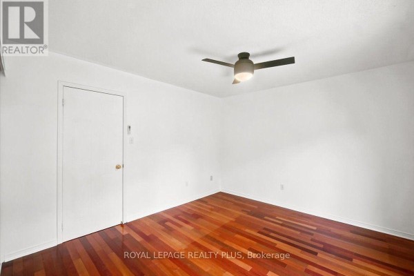 Bedroom with white walls, wood floor, ceiling fan, and closet door. - 15 - 45 Bristol Road E, Mississauga