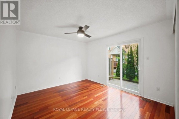Bedroom with white walls, wood floor, ceiling fan, and sliding glass door to backyard patio. - 15 - 45 Bristol Road E, Mississauga