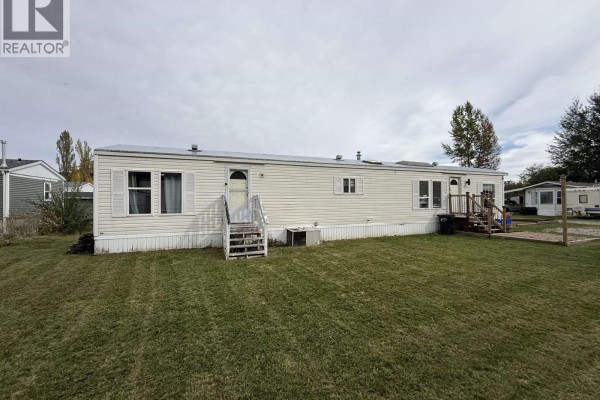 Rear view of a white mobile home with green grass surrounding it. - 15 3211 Gook Road, Quesnel