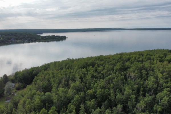 Aerial view of a vast lake and tree-lined shore with scattered houses. - #15 62064 Range Road 133, Rural Smoky Lake County