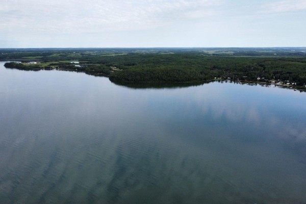 Aerial view of a wide lake and distant shoreline with scattered buildings and trees. - #15 62064 Range Road 133, Rural Smoky Lake County