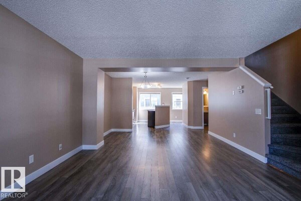 Living room looking towards the kitchen and a staircase with carpeted steps. - #15 8304 11 Av Sw, Edmonton