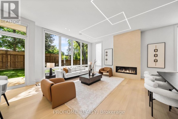 Open concept living and dining area with light wood floors, glass staircase, and large windows overlooking backyard. - 15 Aldershot Crescent, Toronto