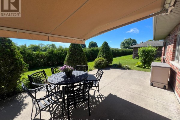 Side view of townhouse with large lawn, trees, and clear blue sky. - 15 Bayfield Mews Lane, Bluewater