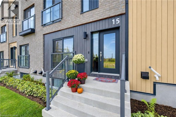 Front entrance of townhouse 15 with concrete steps, pumpkins, and glass double doors facing a field. - 15 Benninger Drive, Kitchener