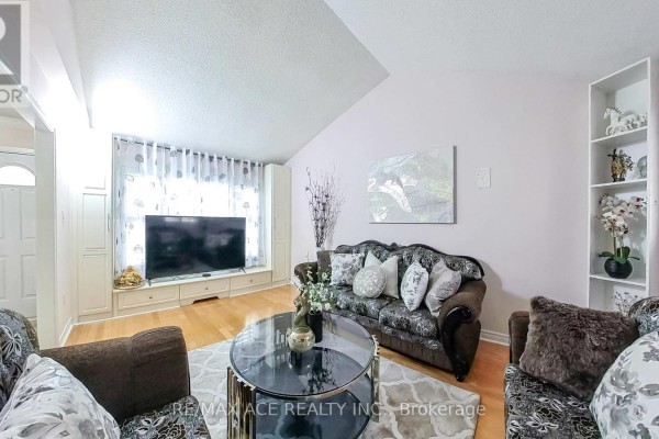 Living room featuring a large TV, decorative sofa set, and high ceilings - 15 Brennan Road, Ajax
