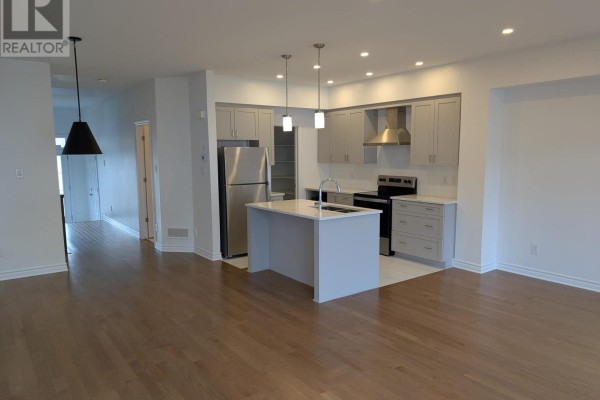 Open concept living area with a grey island kitchen and stainless steel appliances. - 15 Brixton Way, Ottawa