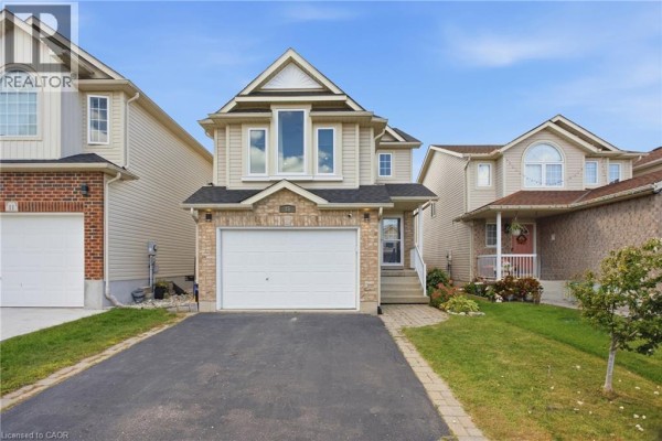 Exterior view of a two-story home with a beige facade, brick accents, and a double-wide garage. - 15 Cannes Street, Kitchener