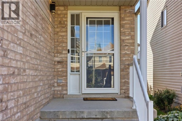 Close-up of the front entrance, showing a brick wall, a screen door with glass panes, and white railing. - 15 Cannes Street, Kitchener