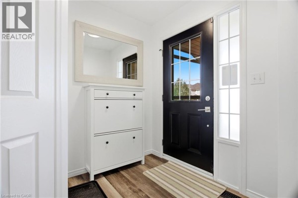 Interior entryway with white walls, a shoe cabinet, a black front door with glass sidelights, and wood-look flooring. - 15 Cannes Street, Kitchener