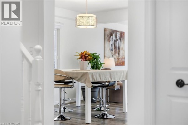 View of a small dining area with a table, two bar stools, a decorative lamp, and artwork on the wall. - 15 Cannes Street, Kitchener