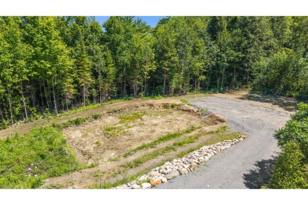 Aerial view of cleared lot with grassy berms, gravel road, and forest backdrop. - 15 Ch. Du Cristal, La Peche