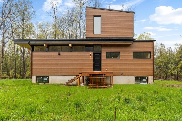 Close-up front view of a modern home with brown siding and a black door. - 15 Ch. Mcgarry, La Peche