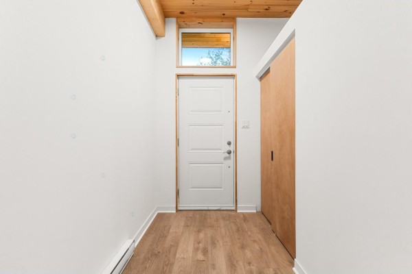 Interior hallway with a white front door, wood-look flooring, and a sliding closet door. - 15 Ch. Mcgarry, La Peche
