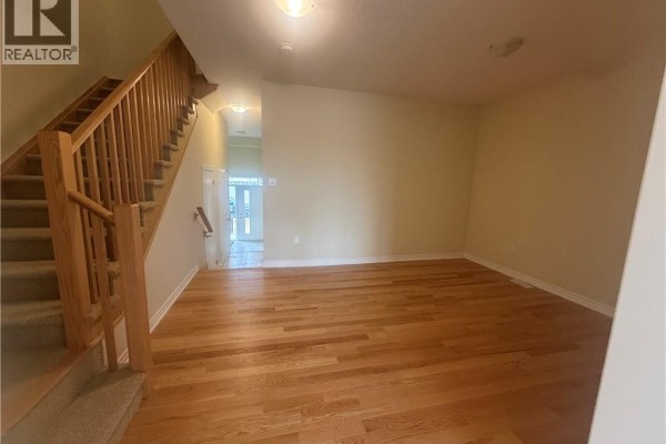 Living room with light beige walls, hardwood floors, and wooden staircase with carpeted steps. - 15 Chapman Road, Paris