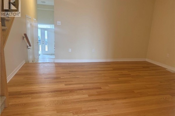 Living area with light beige walls, hardwood floors, and view of the entryway. - 15 Chapman Road, Paris