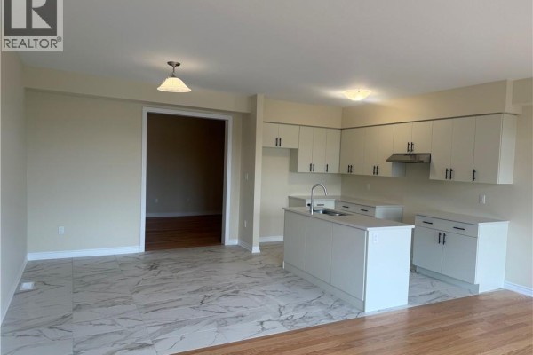 Kitchen with white cabinets, island, stainless steel appliances, and marble tile flooring. - 15 Chapman Road, Paris