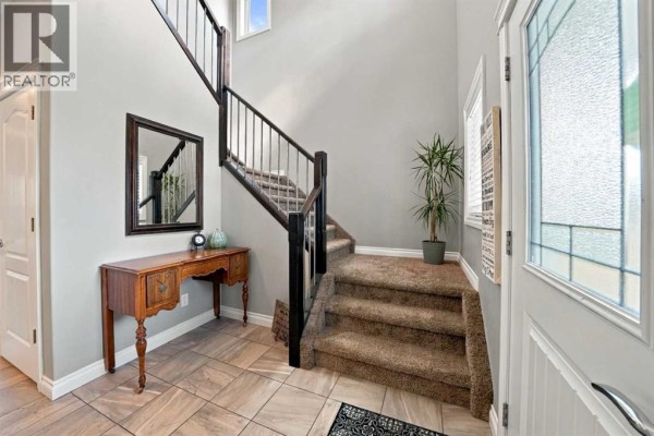 Entrance hallway with a staircase, a wooden console table, and a large mirror. - 15 Cole Way, Sylvan Lake