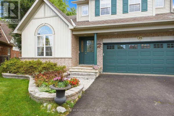 Close-up view of the front entrance, showing a stone walkway, landscaping, and dark green garage door. - 15 Costigan Court, Halton Hills