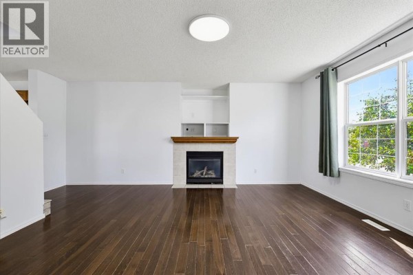 Open concept living space with dark hardwood floors and gray walls. - 15 Coventry Link Ne, Calgary