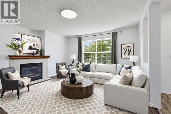 Living room with dark hardwood floors, a large window, and an opening to the entryway. - 15 Coventry Link Ne, Calgary