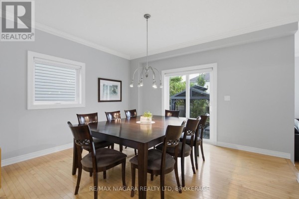 Wooden dining table with 8 chairs, chandelier, and backyard view - 15 Cozocar Crescent St Catharines