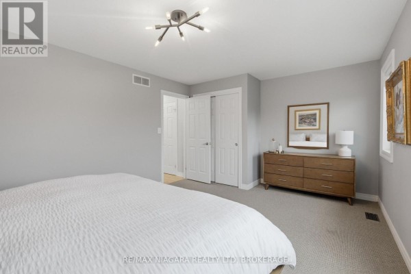 Living room with hardwood floors, entertainment unit, leather sofa, and staircase. - 15 Cozocar Crescent, St  Catharines