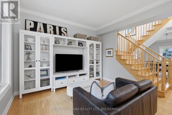 Living room with entertainment unit, sofa, and wooden staircase - 15 Cozocar Crescent St  Catharines
