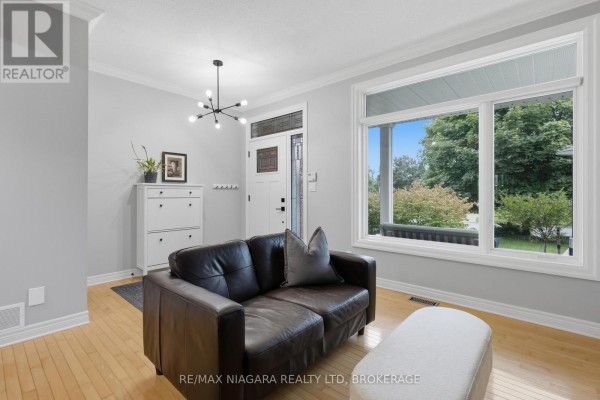Leather sofa and ottoman in living room with hardwood floors and large window - 15 Cozocar Crescent St Catharines