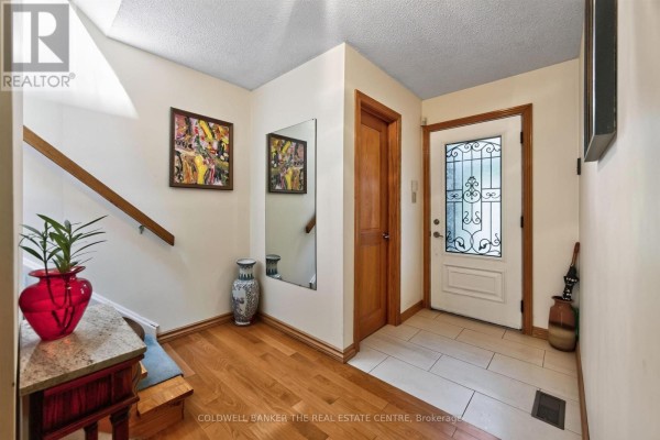 Interior view of a hallway with hardwood floors, wooden doors, and a staircase. - 15 Craiglee Drive, Toronto