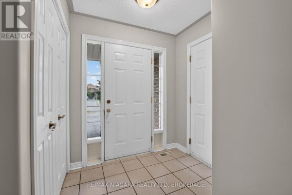 Interior entryway with a white front door, beige tile floor, and beige walls. - 15 Days Avenue, Welland