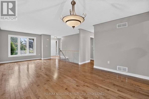 Living room with hardwood floors, gray walls, a large window, and an open doorway. - 15 Days Avenue, Welland